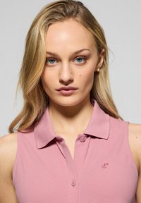 Polo shirt senza maniche di colore rosa con colletto, patta dei bottoni e piccolo logo ricamato sul petto. Texture in cotone liscia.