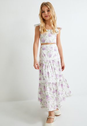Ensemble floral en deux pièces comprenant un crop top blanc à épaules volantées et une jupe longue assortie ornée de fleurs violettes et d'une bordure en dentelle.