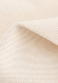 Tissu en coton beige avec un tissage texturé, présentant de douces plis et une finition douce, mettant en valeur sa surface lisse et sa couleur neutre.