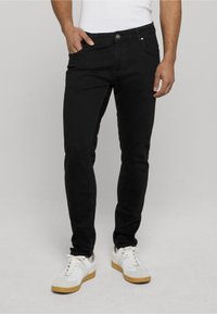 Melni džinsi ar slaidu piegriezumu, ar priekšējām kabatām un pogu aizdari. Apvienoti ar baltām kedām un vienkāršu baltu kreklu.