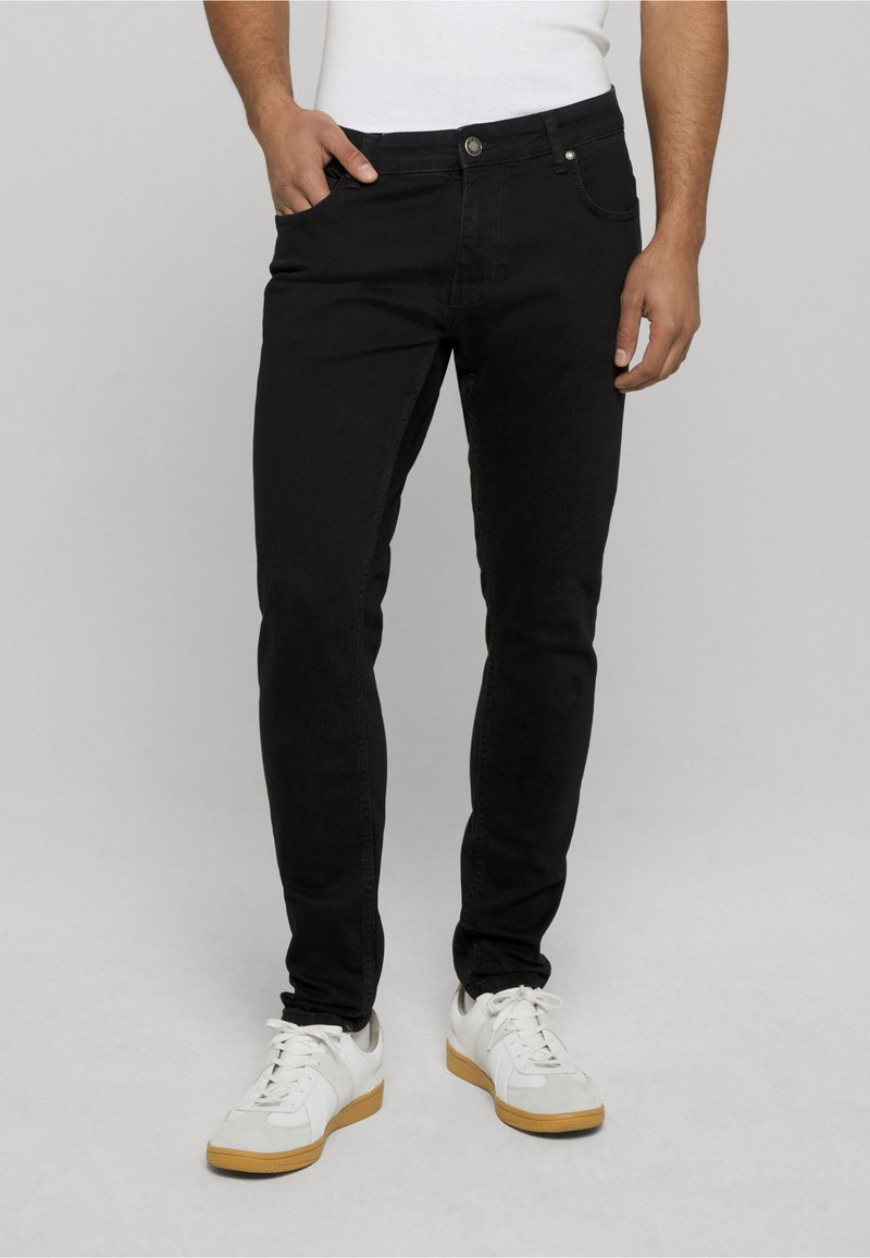 Melni džinsi ar slaidu piegriezumu, ar priekšējām kabatām un pogu aizdari. Apvienoti ar baltām kedām un vienkāršu baltu kreklu.