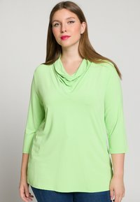 Lys grøn cowl neck top med trekvartærmer, lavet af blødt stof. Har en afslappet pasform med en glat, ensartet tekstur.