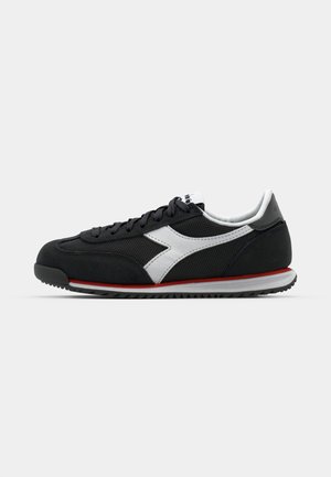 Schwarzer Sportschuh mit einer Oberseite aus Wildleder und Netzmaterial, ausgestattet mit einem weißen Logo, grauen Akzenten und einem roten Streifen entlang der Sohle.
