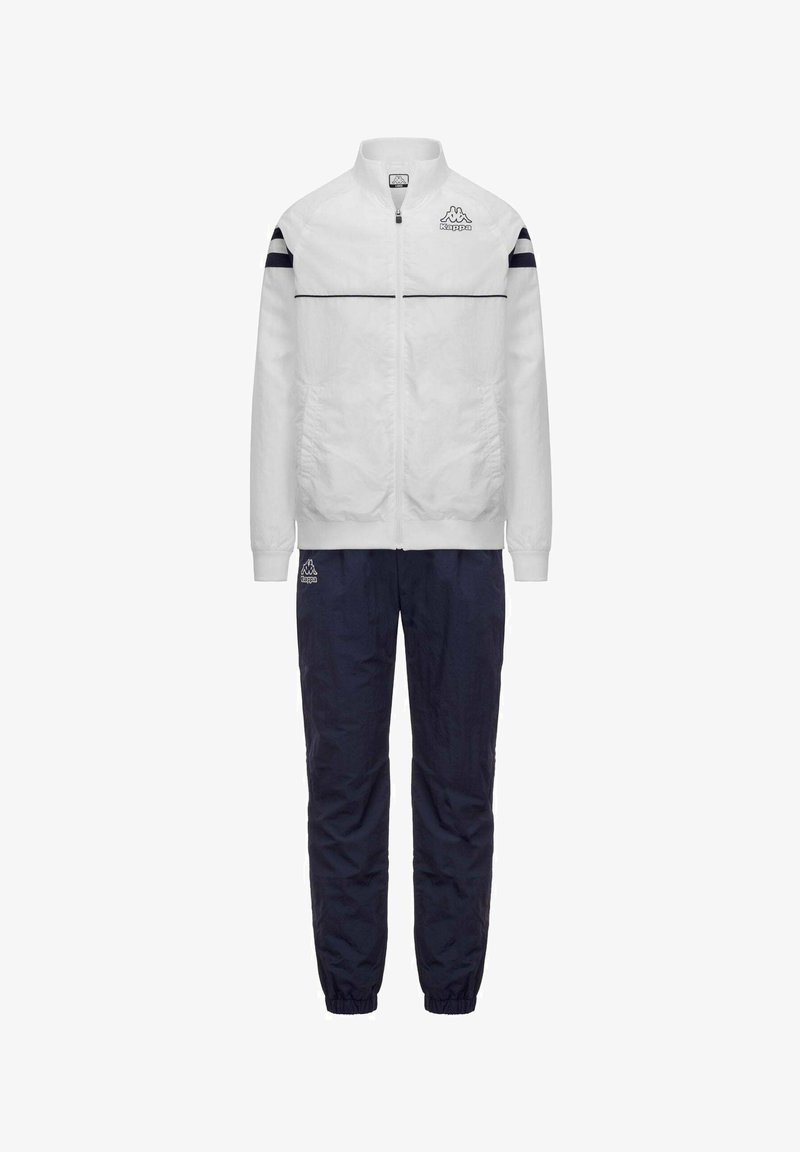Giacca bianca con zip e strisce nere sulle maniche e pantaloni blu navy, entrambi con logo Kappa sul petto e sulla coscia.