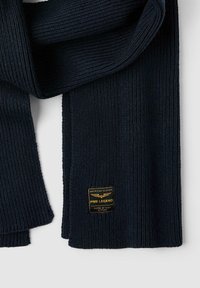 Marine gebreide sjaal met een geribbelde textuur en een merklabel met gouden accenten. Het ontwerp is rechthoekig en zacht aanvoelend.