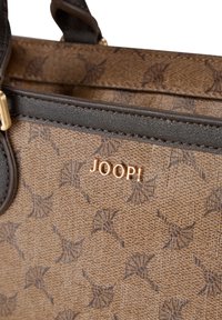 Bolso marrón texturizado con detalles en cuero oscuro. Presenta un patrón repetido de hojas y un logotipo "JOOP!" en tono dorado en el exterior.