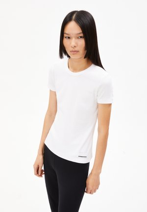 T-shirt bianca a maniche corte in cotone con texture a coste, scollatura rotonda e un piccolo logo nero all'orlo, abbinata a leggings neri.