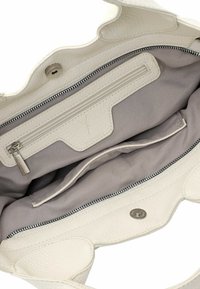 Witte leren handtas interieur met een ritszak en twee open compartimenten. Zachte stofvoering in lichtgrijs. Druksluiting detail zichtbaar.