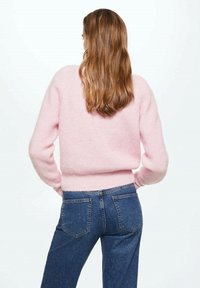 Růžový, nadýchaný svetřík s dlouhými rukávy a žebrovaným lemem, kombinovaný s modrými džínami s klasickým designem kapes.