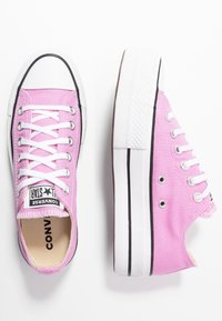Rosa canvas sneakers med vita snören, gummisula och svart trim. Har Converse-logotyp och klassisk design med rund tå.