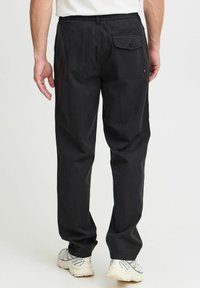 Pantalones negros de corte relajado, con una cinturilla elástica, bolsillos laterales y un bolsillo trasero con cierre de botón.