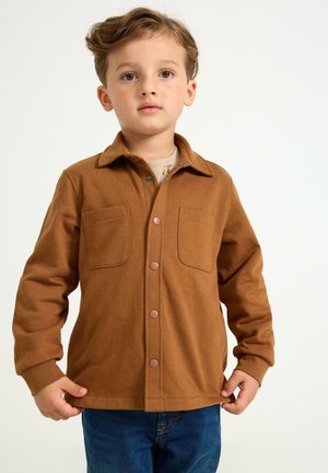 Bruine lange mouwen shirt met twee borstzakken en knoopsluitingen aan de voorkant. Gemaakt van zachte stof met een gladde textuur. Casual pasvorm.