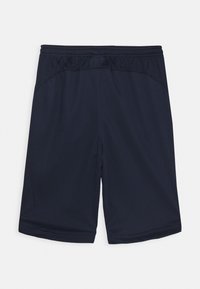 Tummansininen urheilushortsit, joissa on joustava vyötärö, sileä pinta ja polven ylle ulottuva pituus. Ei taskuja tai huomattavia kuvioita.