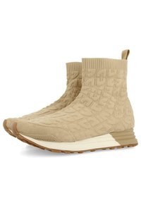 Botines beige con parte superior de punto texturizado y puntera de ante, con una entresuela blanca y suela de goma, destacando un diseño minimalista.