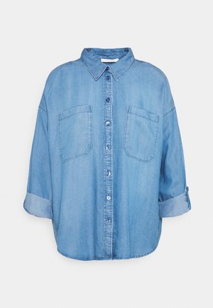Chemise en denim bleu clair à manches longues avec fermeture boutonnée sur le devant, deux poches poitrine, col et manches retroussées.