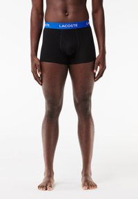 Boxer-briefs noirs avec une ceinture en logo Lacoste bleu, offrant un ajustement confortable et en coton lisse. Pas de motifs ou d'accents supplémentaires.