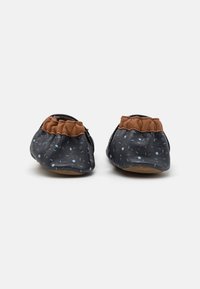 Chaussures en cuir bleu marine avec des pois bleu clair, accents élastiques marron, texture douce et forme arrondie pour un ajustement flexible et un confort optimal.