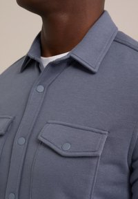 Grijze button-up overhemd van textuurstof, met een kraag, twee voorzakken met kleppen en drukknoopsluitingen.