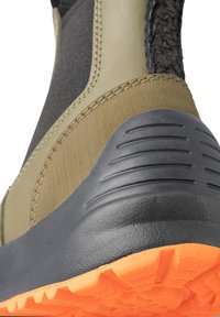 Olivgrön ankelboot med en strukturerad syntetisk ovandel, svart tygpanel och gummi sula i orange med ett taggigt mönster.