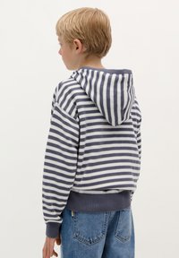 Gestreepte hoodie in grijs en wit, met een capuchon, ribgebreide manchetten en zoom, in een casual fit, gecombineerd met blauwe denim jeans.