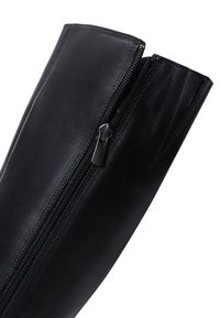 Zwarte leren laars schachtgedeelte met zichtbare zwarte ritssluiting, gedeeltelijk geopend, op witte achtergrond.