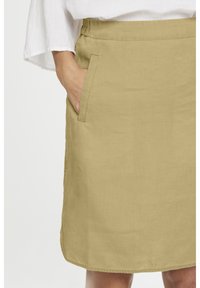 Jupe en lin kaki à coupe décontractée, dotée d'une taille élastique et de poches latérales. Texture lisse et longueur jusqu'aux genoux.