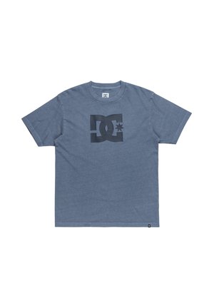 Šedé bavlnené tričko s okrúhlym výstrihom, so veľkým čiernym logom DC uprostred. Krátke rukávy a rovný lem.