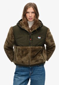 Olive green puffer jacket featuring a faux fur lower section, zip closure, hood, and side pockets. Soft texture with contrasting materials.
