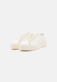 Valged sneakerid siledast materjalist, ümarate varvastega, nööridega disain ja tekstuuriga platvormi tallaga. Minimalistlik stiil koos delikaatsete aktsentidega.