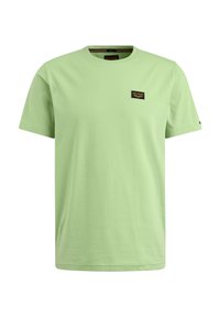 Camiseta de algodón verde claro con mangas cortas, cuello redondo y un pequeño parche negro con texto en el área del pecho izquierdo.