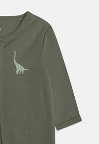 Olivengrøn baby body med lange ærmer, med et lysegrønt dinosaur grafik på brystet og en glat, blød tekstur.