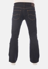 Donkerblauwe denim spijkerbroek met een uitlopende pijpdesign, voorzien van achterzakken met gebogen stiksel en een leren patch in bruin op de tailleband.