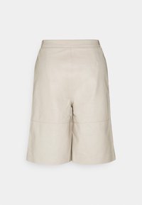 Pantaloni shorts in pelle beige con un design a gamba larga, caratterizzati da una cucitura tonale e due tasche laterali, presentano una texture liscia e opaca.