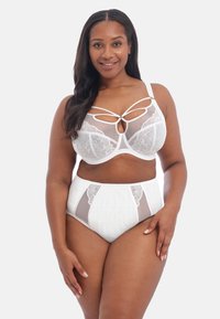Hvidt lingerisæt bestående af en blondemanchet med udsnit og high-waisted trusser. Mesh-paneler fremhæver designet. Glat tekstur.