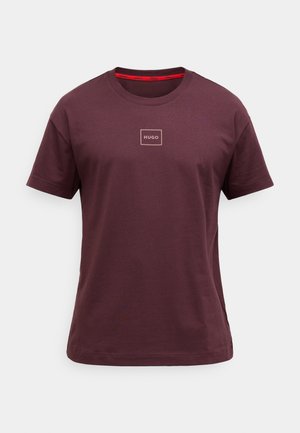 Burgunderfarget bomulls-T-skjorte med korte ermer, rund hals og en liten firkantet logo i midten. Har røde kontrastdetaljer ved kragen.