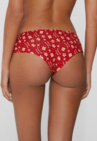 Red holiday-themed cotton briefs featuring a repeating pattern of gingerbread men, stars, and snowflakes in light colors.