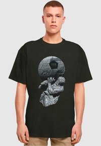 Sort bomulds t-shirt med et grafisk motiv af en stensskulptur, der holder en struktureret fodbold med "FCH" indgraveret. Korte ærmer.