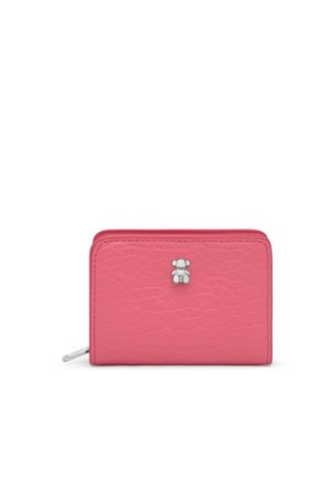 Una cartera rosa con textura y cremallera alrededor, adornada con un pequeño colgante plateado con forma de osito de peluche, aparece sobre un fondo blanco.