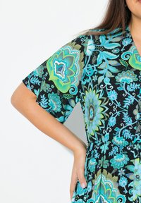 Abito a maniche corte di colore nero con intricati motivi floreali blu e verdi, presenta una vita stretta e bottoni. Tessuto leggero.
