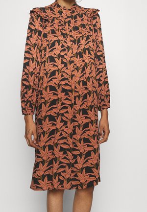 Robe noire longueur genou avec manches longues, motif floral orange, col haut froncé et épaules légèrement bouffantes.