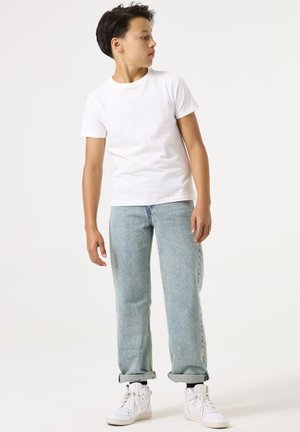 Witte katoenen T-shirt, lichtblauwe denim jeans, opgerolde mouwen en witte hoge sneakers. Eenvoudig ontwerp en ontspannen pasvorm.