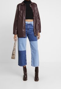 Bourgondische faux leren jas, zwart geribbeld crop top, patchwork blauwe denim rechte broek, gestructureerde bruine laarzen en een handtas met slangenprint.