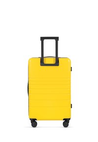 Yellow hard-shell suitcase with a glossy finish, vertical ridges, black wheels, and a retractable handle. Front view, no additional details.