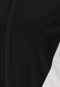 Black fabric with a smooth texture, featuring a central zipper and a white accent. The design is minimalistic and tailored.