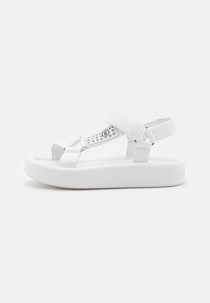 White platform sandals made of synthetic material featuring adjustable strap design, smooth texture, and molded footbed for comfort.