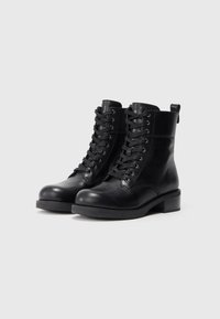 Mustad mustad nahast kõrge säärega kingad ümmarguse varbaga, nööpide ja madala neljakandilise kontsaga. Tagaküljel on lihtsaks selga panemiseks tõmbeauk.