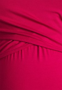 Tejido de jersey fucsia con detalles fruncidos y un diseño drapeado. Textura suave con costuras visibles. Material blando y elástico.