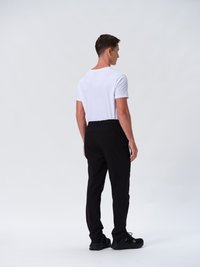 Männliches Outfit mit einem schlichten weißen T-Shirt und schwarz tapering Hosen. Die Hosen haben eine glatte Textur und subtile Seitentaschen, kombiniert mit schwarzen Sneakers.