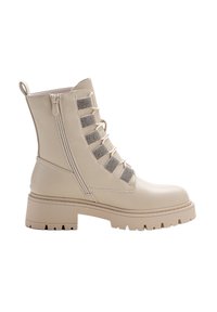 Bottine en cuir beige avec un bout arrondi, fermeture éclair sur le côté et design lacé avec des accents métalliques. Semelle épaisse et texturée pour l'adhérence.