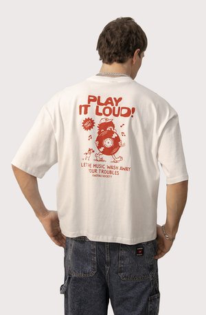 T-shirt ample blanc avec un texte graphique rouge vif et des illustrations au dos, offrant une coupe décontractée et des manches courtes.